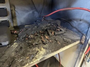 Verkohlte Batteriekomponenten und geschmolzene Kabel auf einer Metallfläche